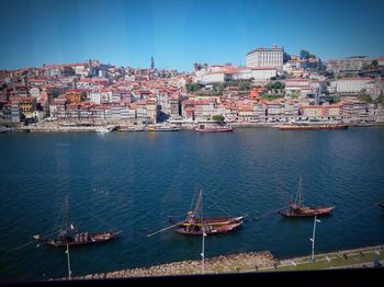 Sailboats in rio douro gaia portugal by buildings against clear sky