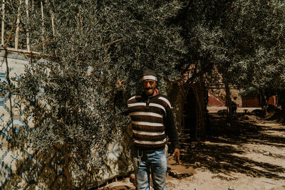 Portrait of young man standing against trees