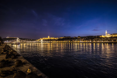 Illuminated chain bridge and buda castle against sky seen from shoes on the danube bank