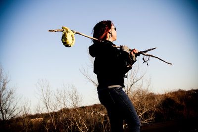 Woman holding stick on field against sky