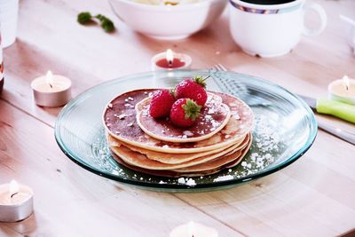 Strawberries on pancakes in plate over table