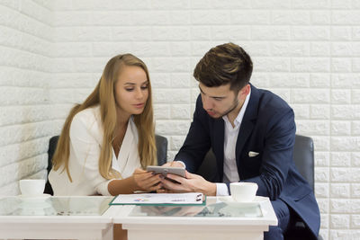 Business colleagues discussing over digital tablet while sitting in office