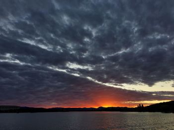 Scenic view of dramatic sky over silhouette mountain during sunset