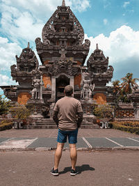 Full length rear view of man walking outside temple against building