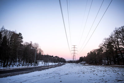 Snow covered field against clear sky during winter