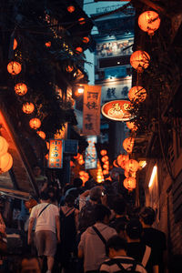 Illuminated lanterns hanging over people at night