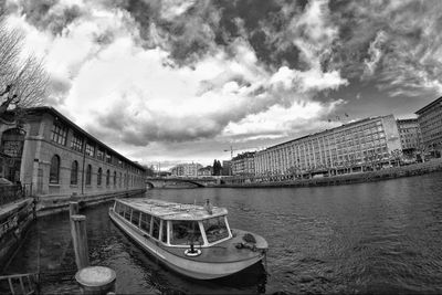 Boat in city against cloudy sky
