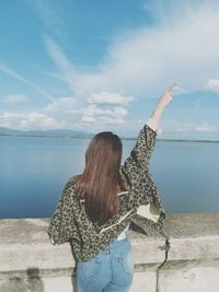 Rear view of woman standing at observation point by sea against sky