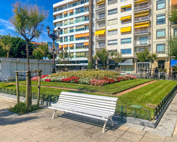 Empty park bench by building in city