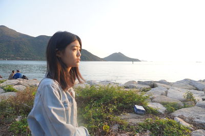 Young woman looking at sea against sky