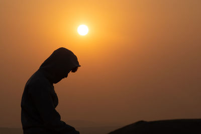 Silhouette man standing against orange sky during sunset