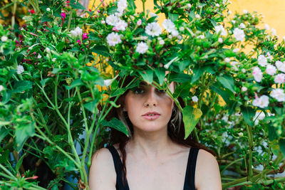 Portrait of young woman standing against plants