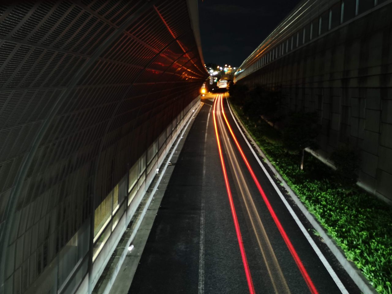 LIGHT TRAILS ON ROAD IN ILLUMINATED CITY