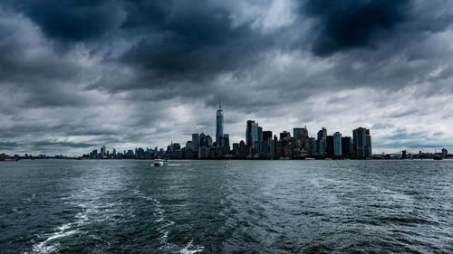 City by river against storm clouds