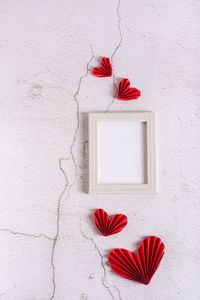 Paper red diy hearts around an empty photo frame on a concrete background. valentine's day. 