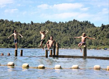 People on riverbank against sky