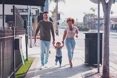 Family of three walking in downtown, baby boy walking with parents