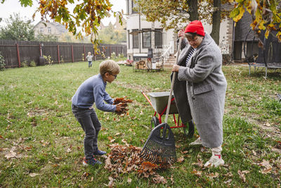 Mother with son raking dry leaves in back yard