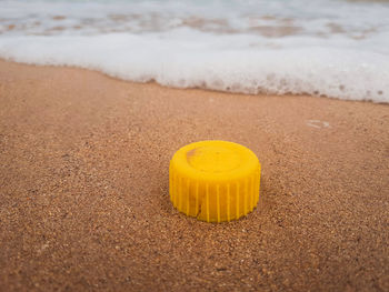 Close-up of yellow plastic bottle cap on beach