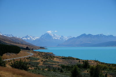 Scenic view of sea and mountains against clear blue sky