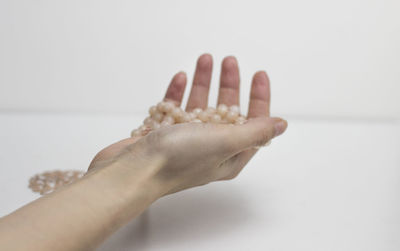 Close-up of hand holding ice cream over white background