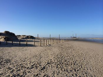 Scenic view of beach against clear blue sky