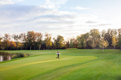 People on golf course against sky