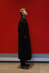 Profile view of man standing against red wall