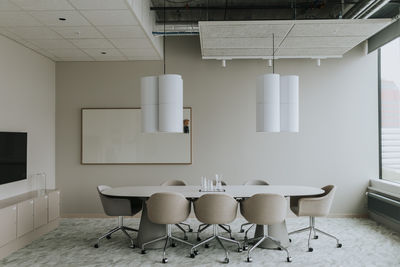 Empty conference table with chairs and pendant light in board room
