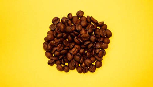 High angle view of coffee beans against yellow background