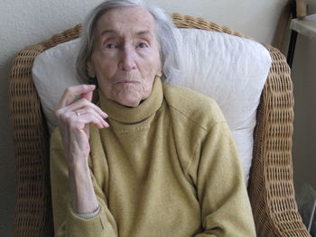 Portrait of senior woman sitting on seat at home