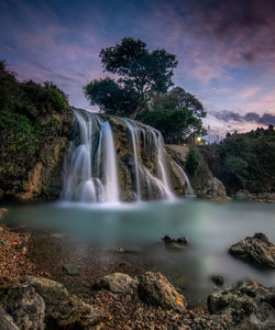 Scenic view of waterfall against sky