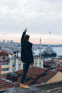 Rear view of man standing in city against sky