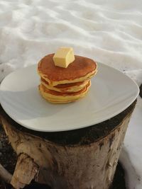 High angle view of pancake in plate on tree stump