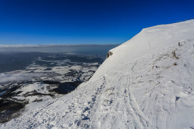 Scenic view of snowcapped mountains against blue sky