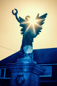 Low angle view of angel statue against sky during sunset