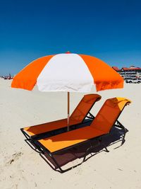 Orange umbrella on beach against clear sky