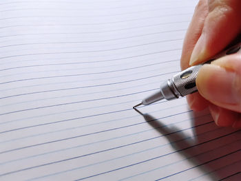 Close-up of hand holding pen on blank lined paper