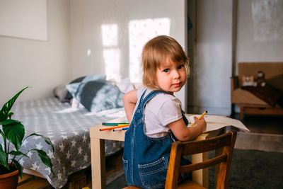 Small child at home at the children's table draws with felt-tip pens.