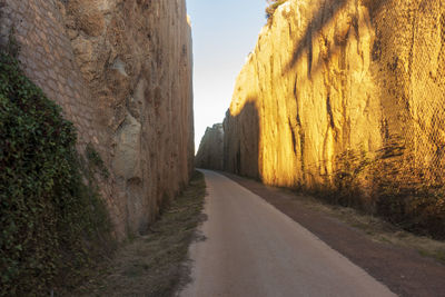 Empty road amidst rocks against sky