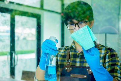 Young man cleaning window at home