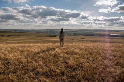 Rear view of man standing on field against sky