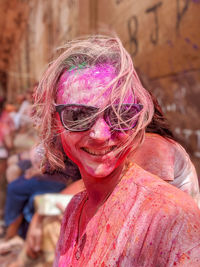 Portrait of woman celebrating holi with pink and red powder paint