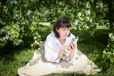 Young woman using mobile phone while sitting outdoors