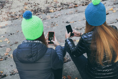 Girls with wool cap sitting in the park using smartphone. teen using mobile phone chat with friends