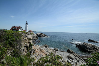 Lighthouse by sea against sky