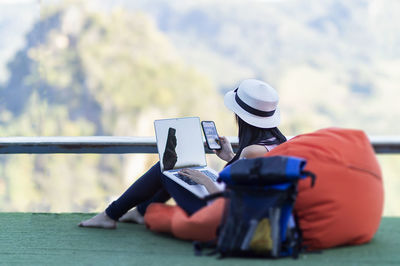 Midsection of person wearing hat sitting outdoors