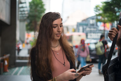 Young woman using mobile phone in city