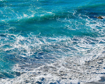 Aquamarine colorful ocean waves and surf with white sea foam