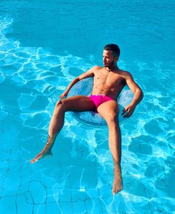 Full length of shirtless man swimming in pool